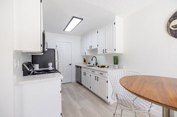 A white kitchen with white cabinets and a wooden table and counter top